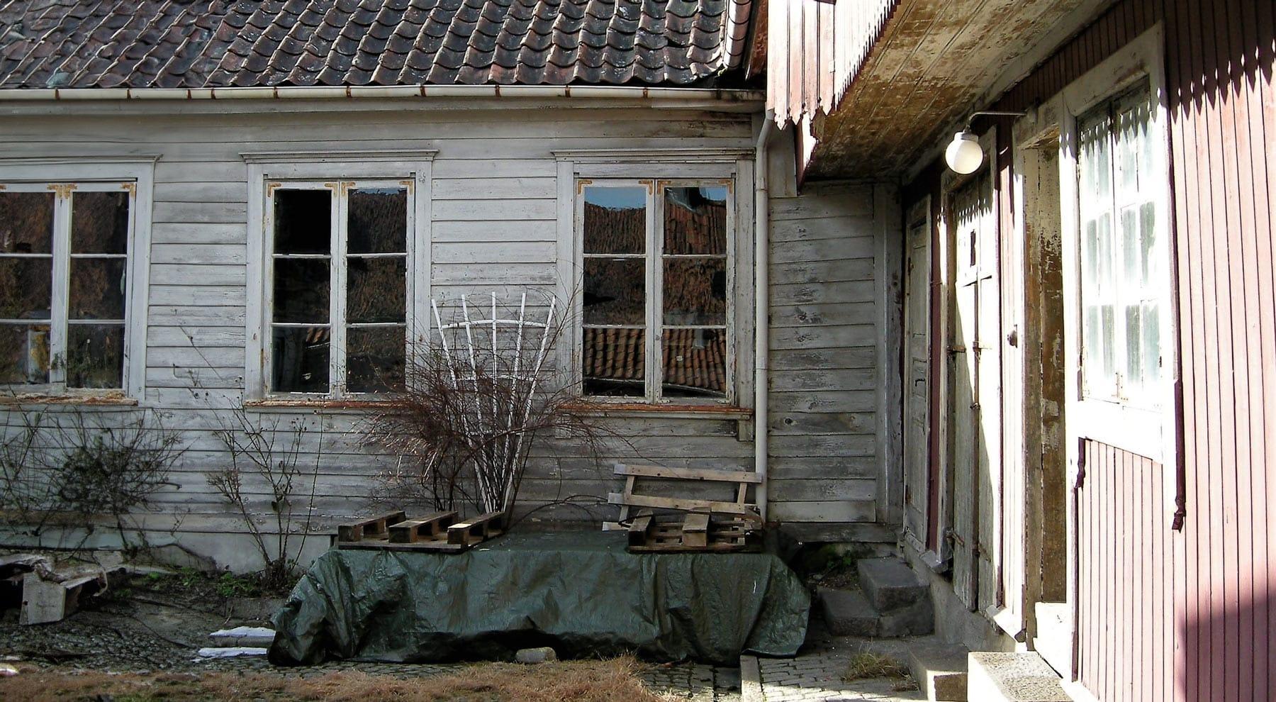 An old white wooden house with small-paned windows and a garden in front
